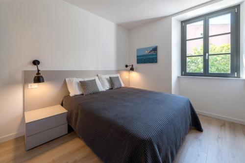 a white bedroom with a large bed and a window at Residence La Torre con private park in Trieste