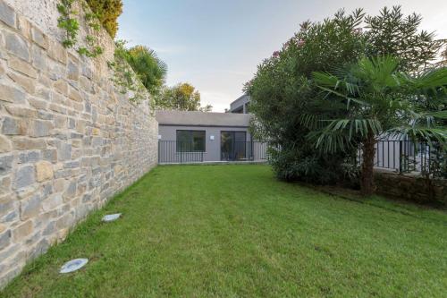 a yard with a stone wall and a house at Residence La Torre con private park in Trieste