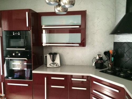 a kitchen with red cabinets and a stove top oven at BEAUN'MAISON Spa Piscine Borne électrique in Beaune