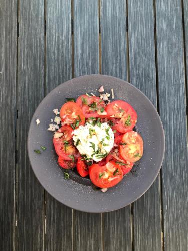 a plate of tomatoes and cheese on a wooden table at Chambre d 'hôtes Chez Manon et Hugo in Béthune