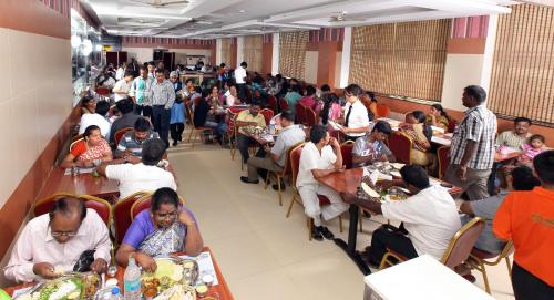 a crowd of people sitting at tables in a restaurant at Hotel Vassi Palaze in Chengalpattu