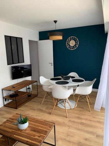 ein Esszimmer mit einem Tisch und weißen Stühlen in der Unterkunft Appartement vue mer in La Baule