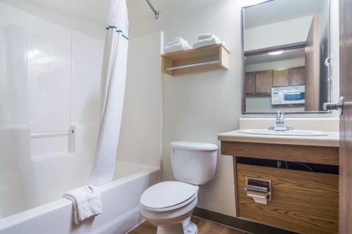 a bathroom with a toilet and a sink and a mirror at HomeTowne Studios & Suites by Red Roof Bentonville in Bentonville