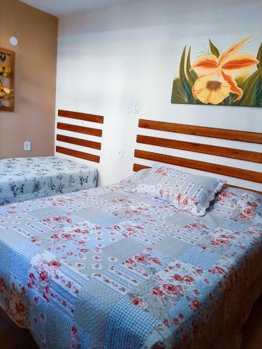 um quarto com duas camas com uma colcha em Suites Oliveira em Arraial do Cabo