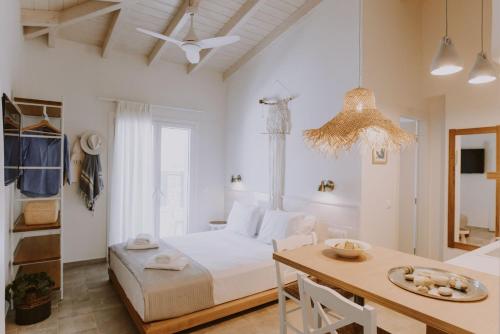 a white bedroom with a bed and a table at ERIEL Boutique Apartments in Lefkada Town