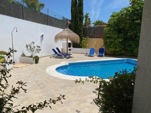 a swimming pool with blue chairs and a house at Villa Casa Maravilla near the coast in Mazarrón
