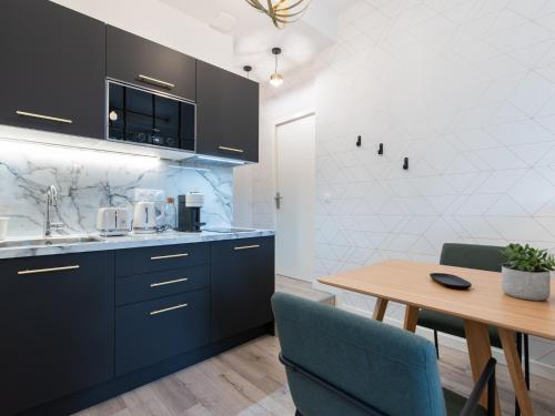 eine Küche mit blauen Schränken und einem Holztisch in der Unterkunft Luxury Studio "Le Chaleureux" - Lyon Part-Dieu - Dreamy Flat Lyon in Lyon