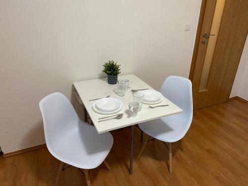 a white table with white chairs and plates on it at SATYS Apartments in Ostrava