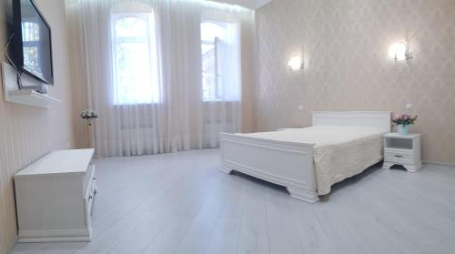 een witte slaapkamer met een bed en 2 ramen bij Vip Apartment in the very center of Odessa with sea view in Odessa