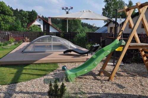 a playground with a slide and an umbrella at Wellness Pension Fulda Černý Důl in Cerny Dul