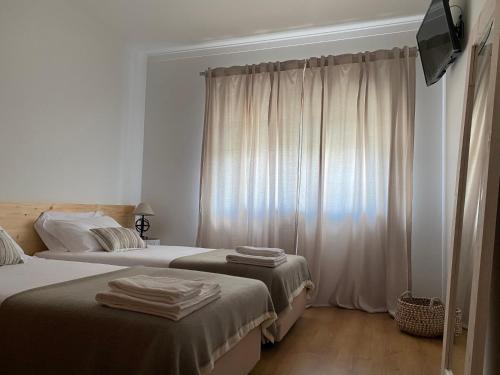 een hotelkamer met 2 bedden en een raam bij ESSENCYAHOMECoimbra in Coimbra