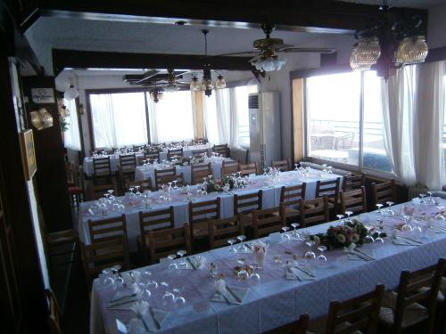 a room filled with tables and chairs with white linens at Daskalio Beach Hotel in Keratea