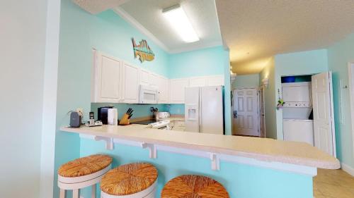 a kitchen with white cabinets and a counter with stools at Windemere Condominiums in Perdido Key