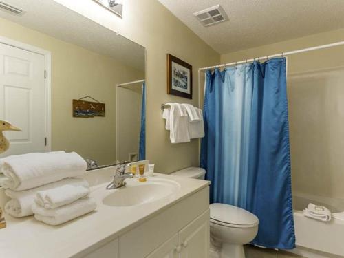 a bathroom with a sink and a toilet and a blue shower curtain at Windemere Condominiums in Perdido Key
