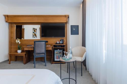 a hotel room with a desk with a television and chairs at Hotel Afa in Pristina