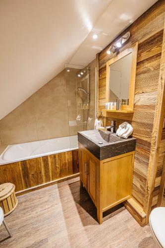 une salle de bain avec un lavabo et une baignoire dans l'établissement Chalet La Perle de L'Oisans - Appartements d'Exception, à Vaujany