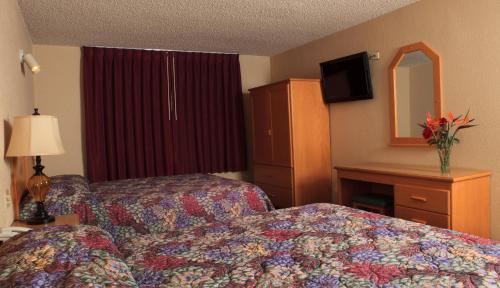 a hotel room with a bed and a dresser and a mirror at La Villa De San Quintin in San Quintín