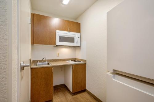 a small kitchen with a sink and a microwave at HomeTowne Studios by Red Roof Philadelphia - Maple Shade, NJ in Maple Shade