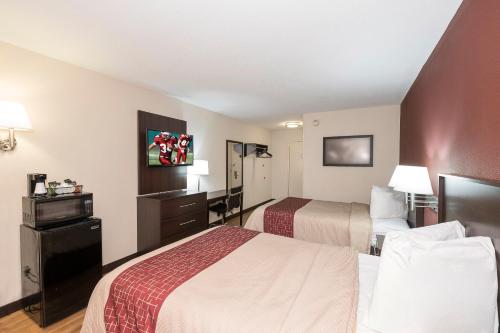 a hotel room with two beds and a television at Red Roof Inn Toledo - Maumee in Maumee