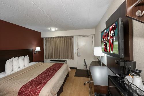 a hotel room with a bed and a flat screen tv at Red Roof Inn Toledo - Maumee in Maumee