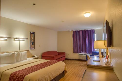 a hotel room with a bed and a red chair at Red Roof Inn Pharr - McAllen in Pharr