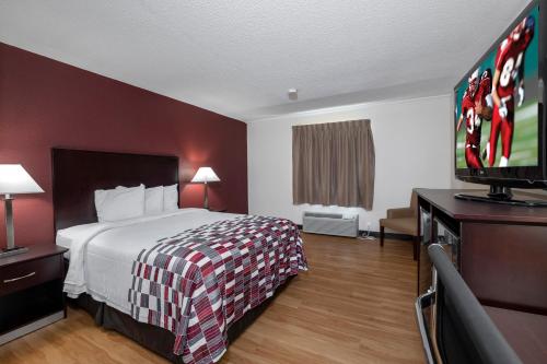 a hotel room with a bed and a flat screen tv at Red Roof Inn Warrenton in Warrenton
