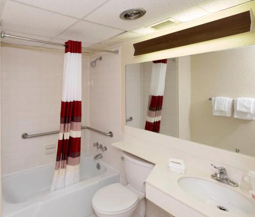 a bathroom with a toilet and a sink and a mirror at Days Inn by Wyndham Williamsport in Williamsport