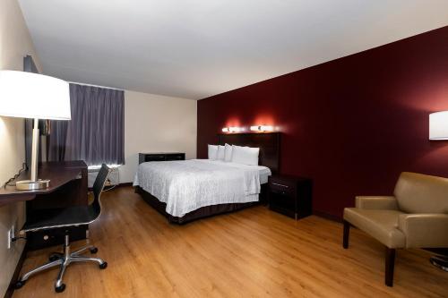 a hotel room with a bed and a desk and a chair at Red Roof Inn PLUS+ Tuscaloosa - University in Tuscaloosa