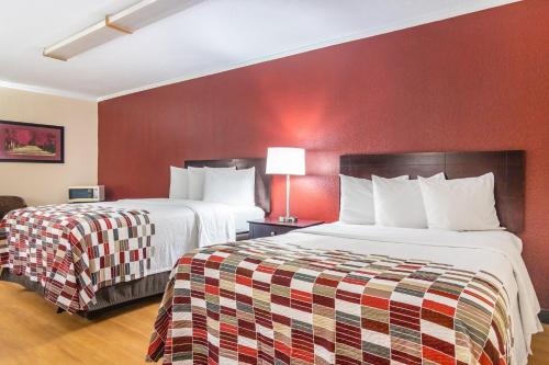 2 Betten in einem Hotelzimmer mit roten Wänden in der Unterkunft Red Roof Inn Ashtabula - Austinburg in Ashtabula