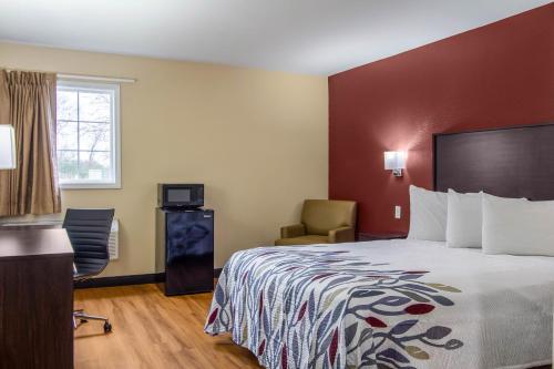 a hotel room with a bed and a chair at Red Roof Inn Perrysburg in Perrysburg