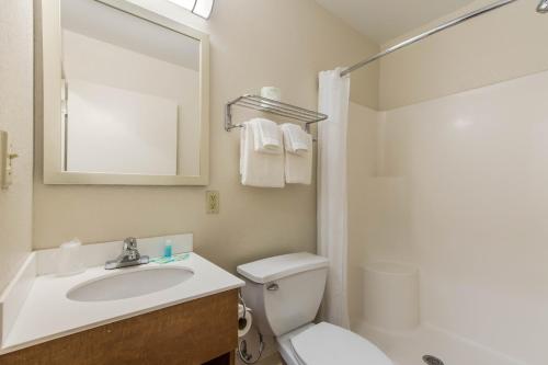 a bathroom with a sink and a toilet and a mirror at HomeTowne Studios by Red Roof Fort Lauderdale in Fort Lauderdale