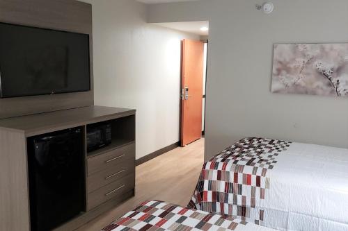 een slaapkamer met een bed en een flatscreen-tv bij Red Roof Inn & Suites Vicksburg in Vicksburg