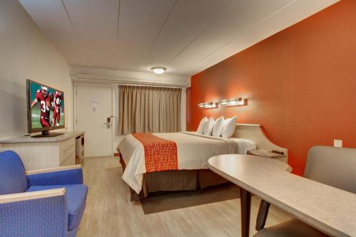 a hotel room with a bed and a table and chairs at Red Roof Inn St Louis - Westport - Maryland Heights in Saint Louis