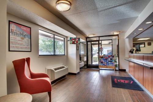 a waiting area with a red chair in a waiting room at Red Roof Inn St Louis - Westport - Maryland Heights in Saint Louis