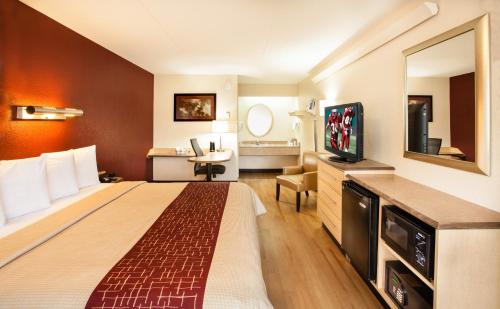 a hotel room with a large bed and a television at Red Roof Inn Louisville East - Hurstbourne in Louisville