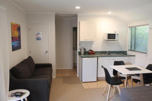 a kitchen and a living room with a couch and a table at Aquarius Motor Inn in Mount Maunganui