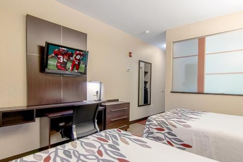 ローカスト・グローブにあるRed Roof Inn Locust Groveのベッドと薄型テレビのある寝室