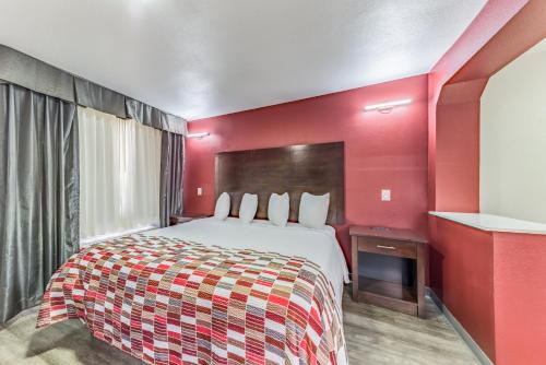 a hotel room with a bed and a red wall at Red Roof Inn Dallas - Mesquite Fair Park NE in Mesquite
