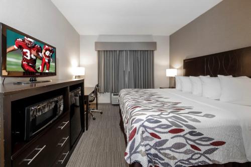 a hotel room with a bed and a flat screen tv at Red Roof Inn & Suites Newburgh - Stewart Airport West Point in New Windsor