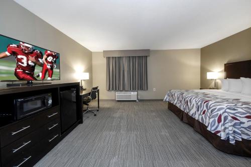a hotel room with a bed and a flat screen tv at Red Roof Inn & Suites Newburgh - Stewart Airport West Point in New Windsor