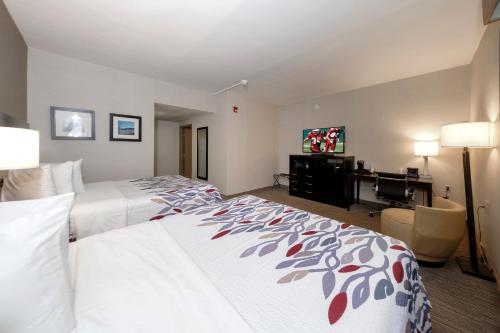 a hotel room with a bed and a flat screen tv at Red Roof Inn & Suites Newburgh - Stewart Airport West Point in New Windsor
