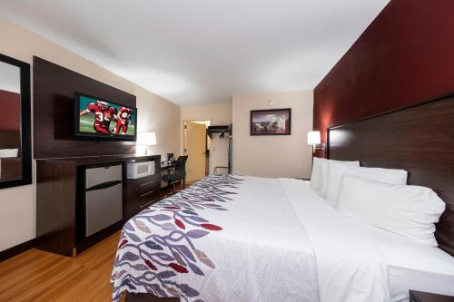 ein Hotelzimmer mit einem großen Bett und einem Flachbild-TV in der Unterkunft Red Roof Inn Bordentown - McGuire AFB in Bordentown