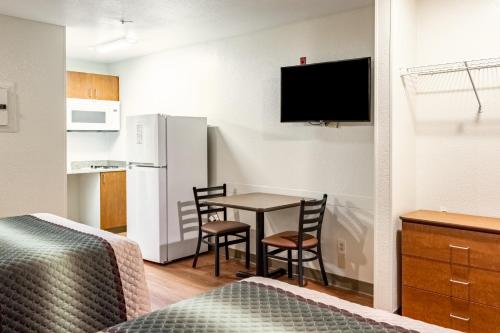 a small room with a table and chairs and a kitchen at HomeTowne Studios by Red Roof Eugene - Springfield in Springfield