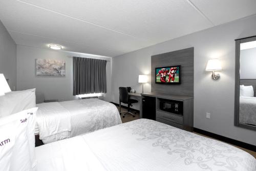 a hotel room with two beds and a desk at Red Roof Inn PLUS Boston - Mansfield - Foxboro in Mansfield