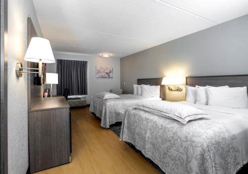 a hotel room with two beds with white sheets at Red Roof Inn PLUS Boston - Mansfield - Foxboro in Mansfield