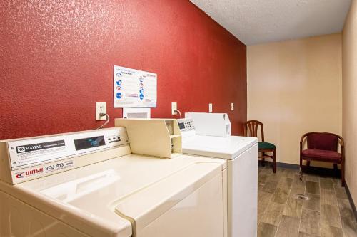 a washing machine in a room with a red wall at Red Roof Inn and Suites Battle Creek in Battle Creek