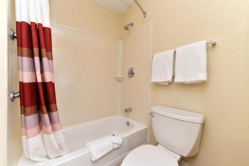 a bathroom with a tub and a toilet and a shower curtain at Red Roof Inn PLUS+ Secaucus - Meadowlands in Secaucus