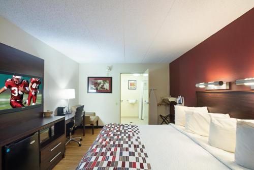 a hotel room with a bed and a desk and a television at Red Roof Inn Madison, WI in Madison