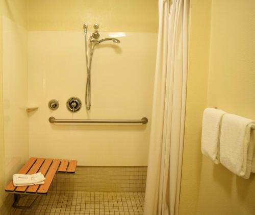 a bathroom with a shower and a wooden bench at Red Roof Inn PLUS+ University at Buffalo - Amherst in Amherst