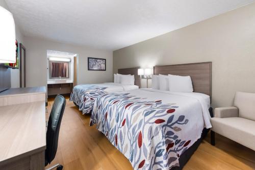 a hotel room with two beds and a chair at Red Roof Inn Dayton - Moraine/U of Dayton in Dayton